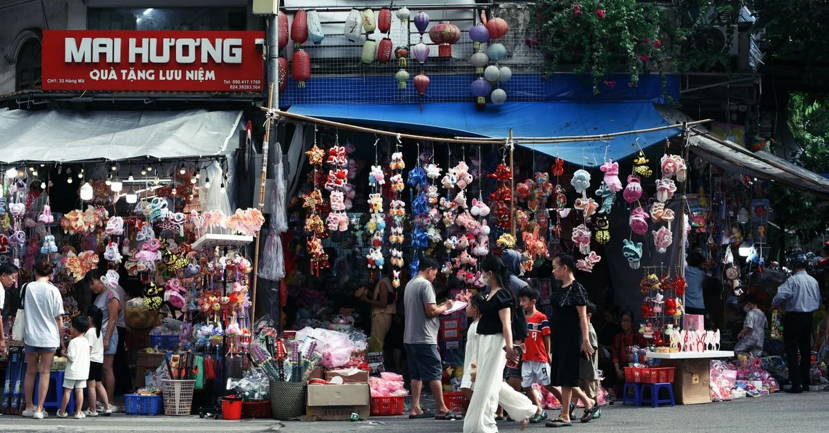 Un marché de rue animé vendant des lanternes colorées et des souvenirs, avec des gens qui font leurs achats.
