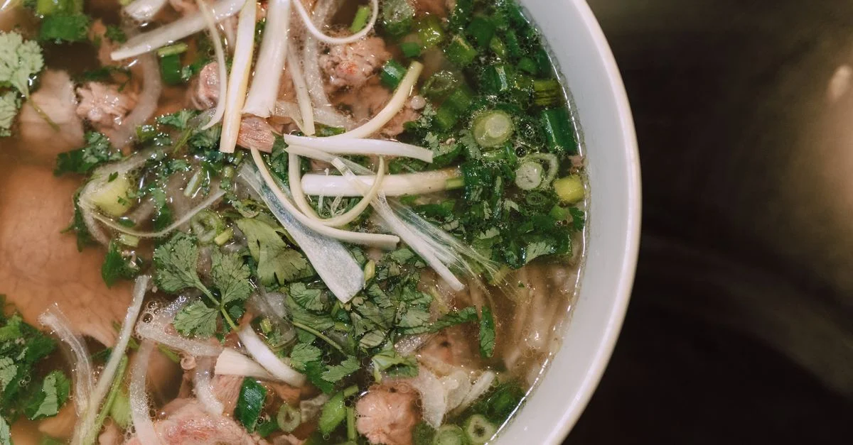 Délicieuse soupe de nouilles Pho vietnamienne avec des herbes fraîches et du bœuf, vue de dessus.