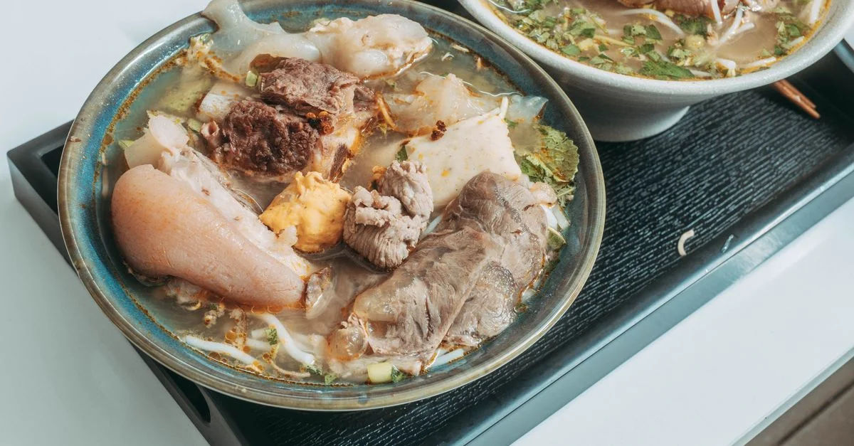 De délicieux bols de soupe pho vietnamienne au bœuf, au porc et aux herbes fraîches, servis sur un plateau.
