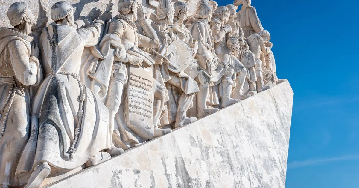 Sculptures en pierre d'explorateurs sur le Monument des Découvertes à Lisbonne contre un ciel bleu.