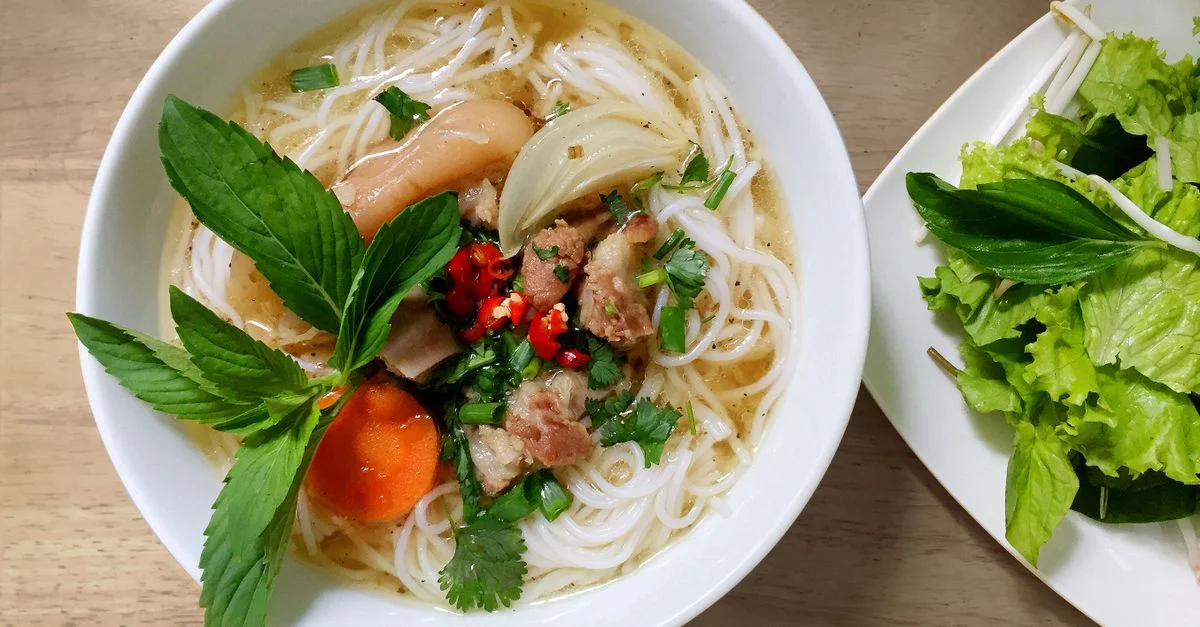 Un bol frais et vivant de soupe de nouilles Pho vietnamienne avec des herbes et des légumes.