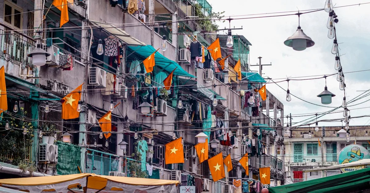 Scène urbaine vietnamienne avec drapeaux, linge étendu et marché en plein air. Une représentation vivante de la vie quotidienne.