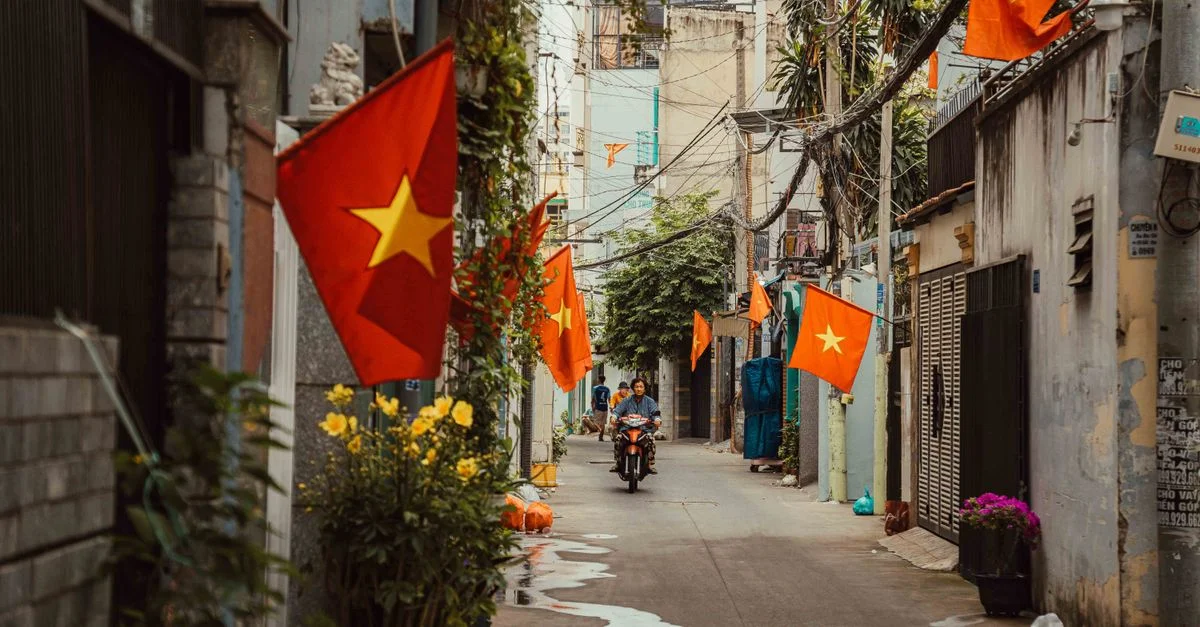 Une ruelle vibrante à Ho Chi Minh-Ville ornée de drapeaux vietnamiens et d'un environnement animé.