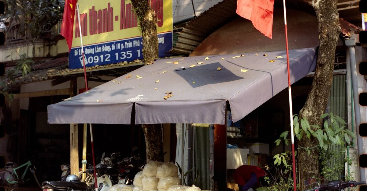 Rue vietnamienne avec des scooters, des drapeaux et une petite boutique.