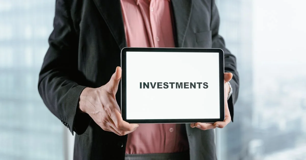 Professionnel tenant une tablette avec le texte 'INVESTISSEMENTS', idéal pour des thèmes financiers et commerciaux.