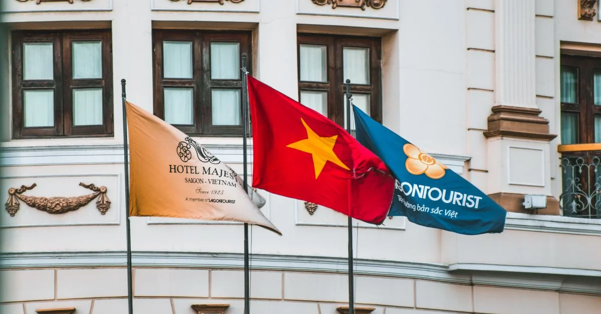 Drapeaux du Vietnam et de tourisme exposés sur la façade de l'Hôtel Majestic Saigon.