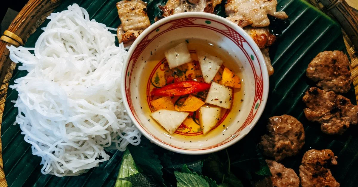 Délicieux Bun Cha servi avec du porc grillé, des nouilles et des herbes fraîches sur une feuille de bananier.