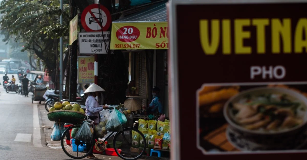 Une scène animée d'un vendeur de rue vietnamien avec un vélo chargé de produits à Hanoi.